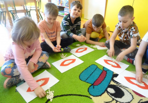 Dzieci układają ziarna fasoli na szablonie ust.